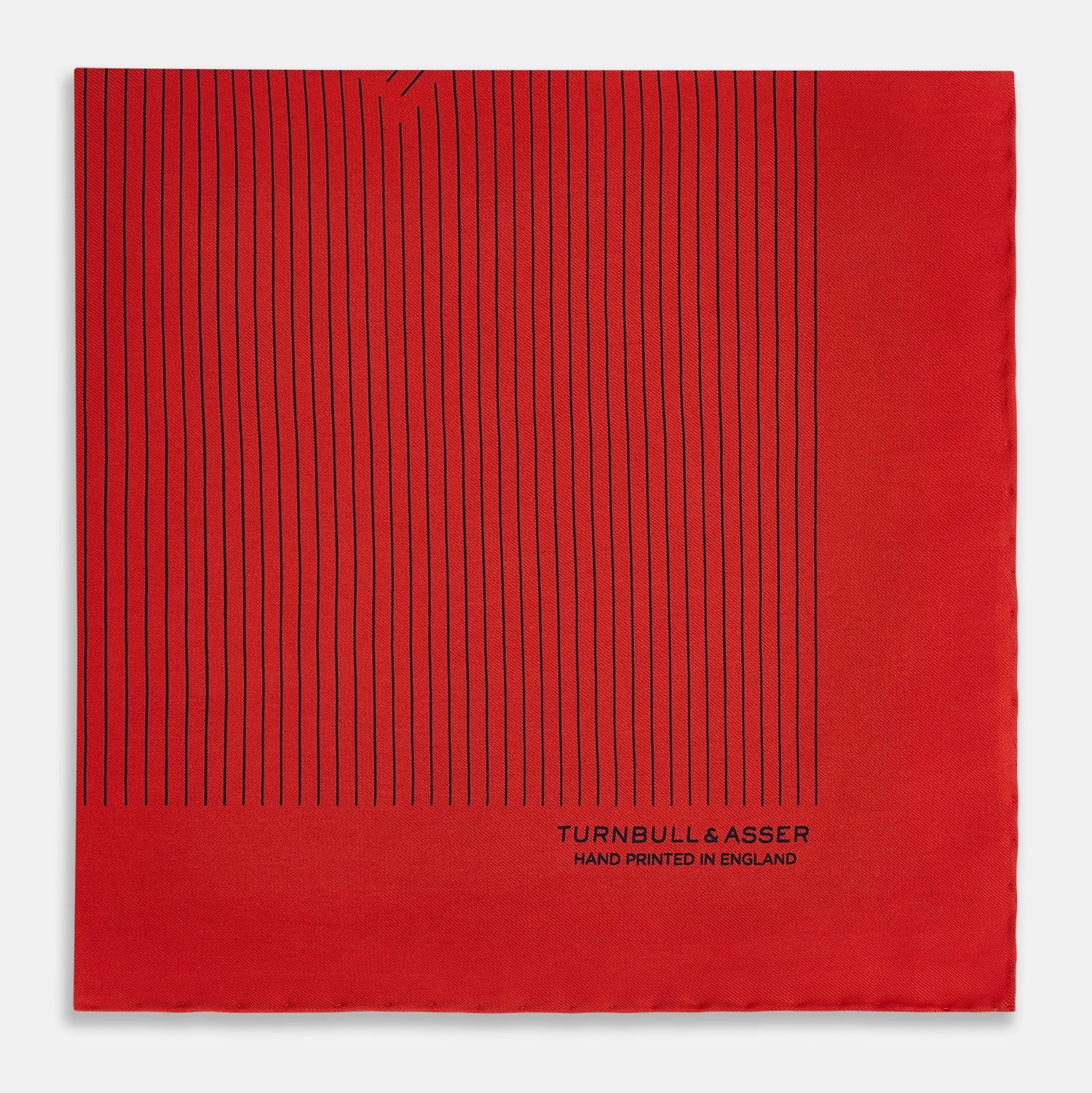 View 4 of product The Red Stripe Silk Pocket Square by Turnbull & Asser features thin black vertical lines and the brand signature in black on one corner, with a neatly folded edge for a touch of classic British style.