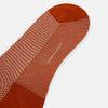 View 3 of product The Turnbull & Asser SOCKS LONG COTTON HOUNDSTOOTH ROSE is a single over-the-calf sock in rusty orange with a white houndstooth pattern and solid orange toe, heel, and cuff, shown on a plain white background.