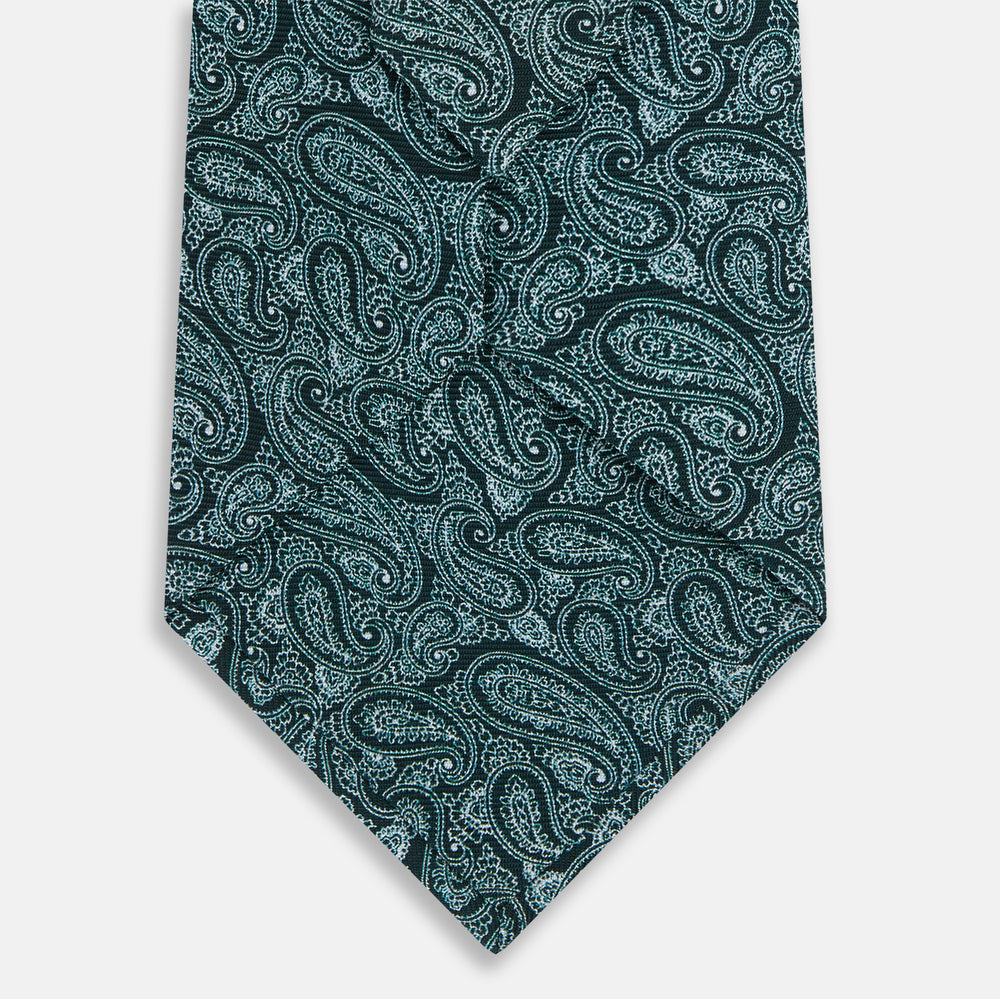 The Turnbull & Asser Light Petrol Paisley Silk Tie features an elegant teal and light blue paisley pattern on white English silk, highlighted by intricate, swirling designs.