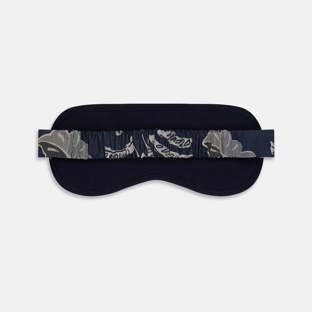 The Turnbull & Asser Navy Bloomsbury Jacquard Cashmere Lined Sleep Mask and Bag features a dark blue backdrop with beige, olive green, and gray floral patterns, plus elastic straps for comfort.