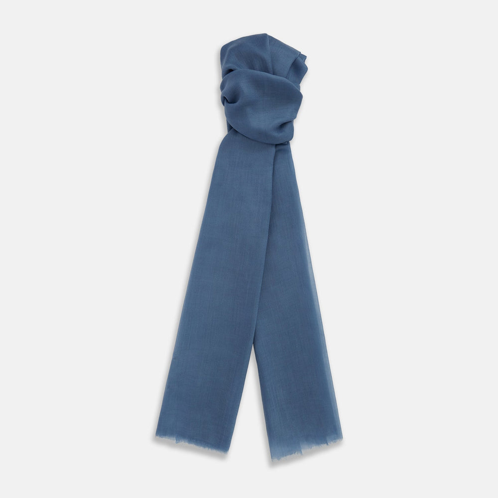 The Turnbull & Asser Mid Blue Cashmere Scarf is lightweight and slightly sheer, hand-dyed with frayed ends, shown loosely knotted against a white background.
