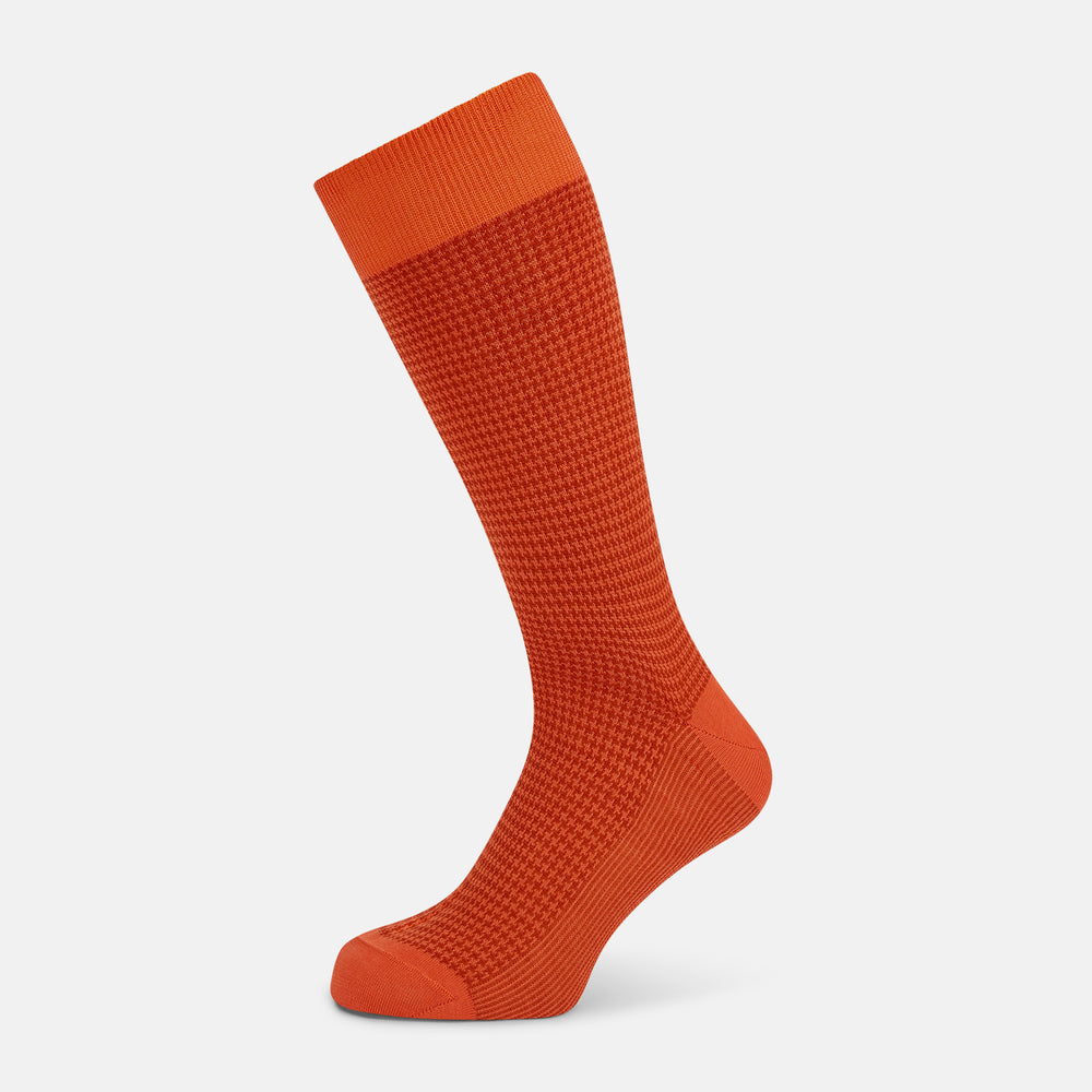 The Orange Houndstooth Mid-Length Socks by Turnbull & Asser feature a bold houndstooth pattern with solid orange toe, heel, and cuff, crafted from soft cotton and shown against a plain white background.