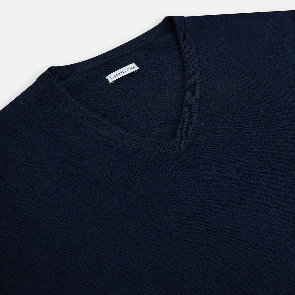 The Turnbull & Asser Navy Cashmere V-neck Jumper features long sleeves with ribbed cuffs and hem, shown against a white background.