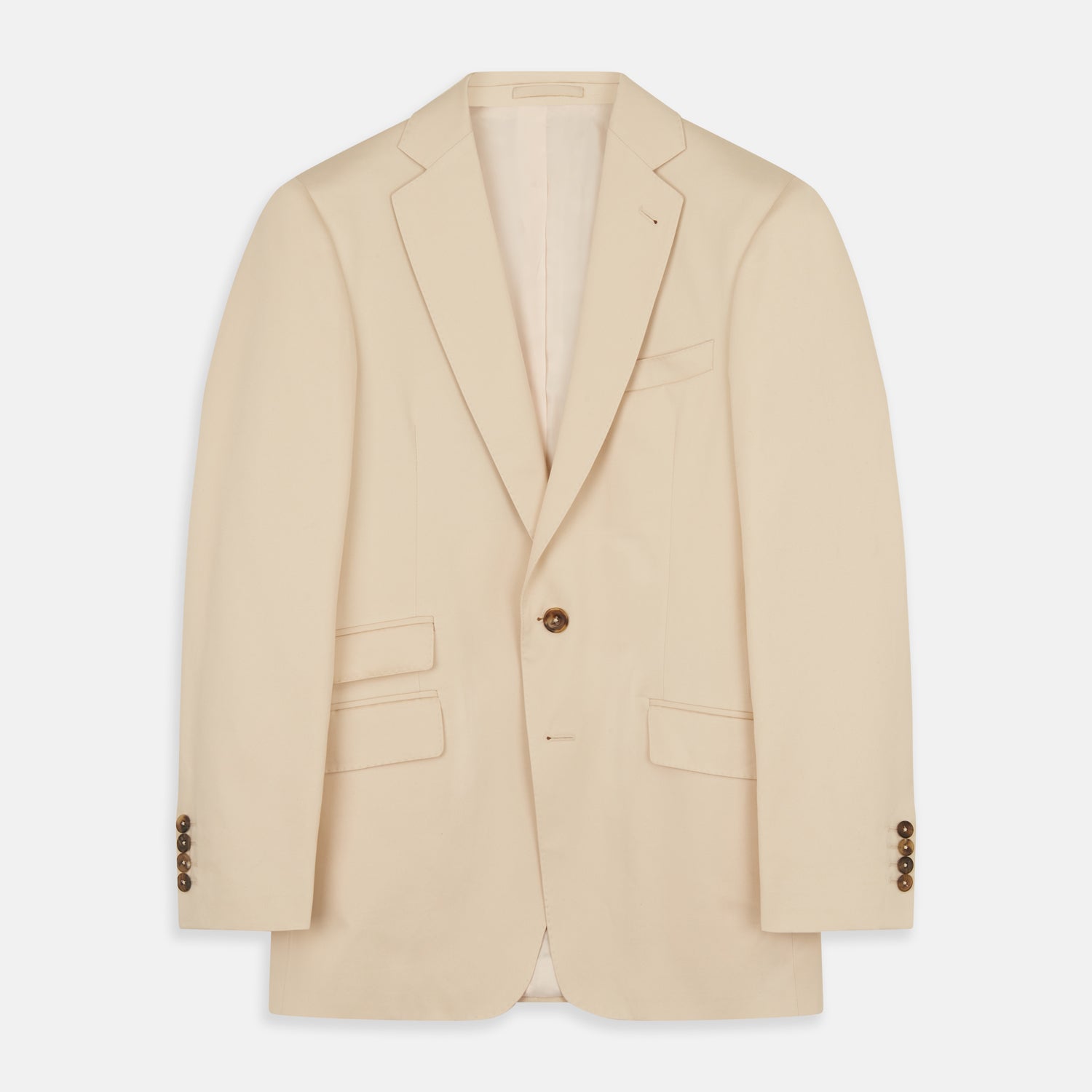 View 2 of product A man in a Turnbull & Asser Beige Cotton Barrington Blazer, light yellow shirt, blue patterned tie, and dark trousers stands against a plain light background, with a pocket square visible and a neutral expression.