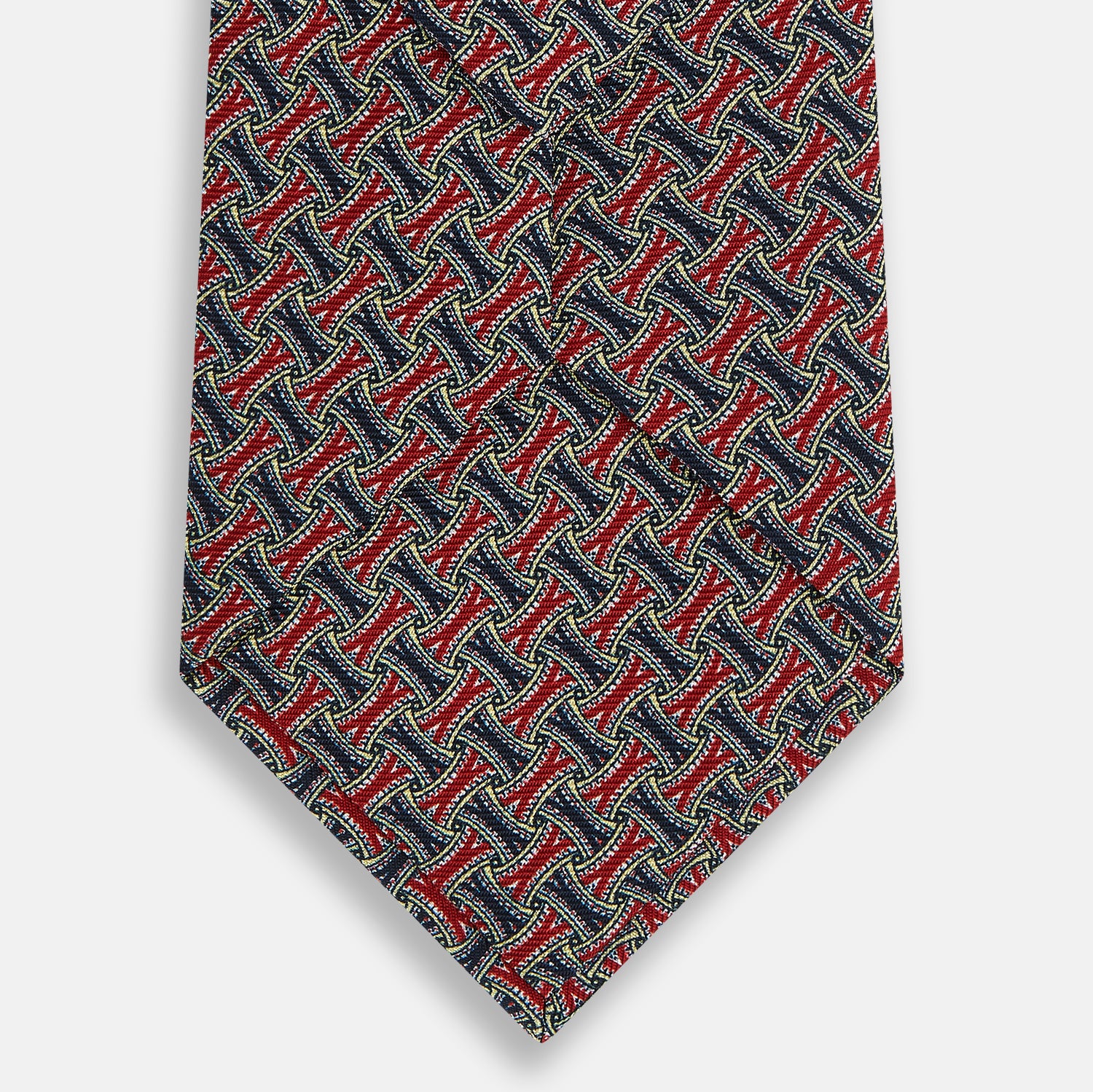 View 3 of product The Turnbull & Asser Red and Navy Weave-Patterned Printed Silk Tie features an intricate geometric design in red, blue, and white. Displayed rolled-up against a plain white background, this classic tie is crafted from luxurious silk.