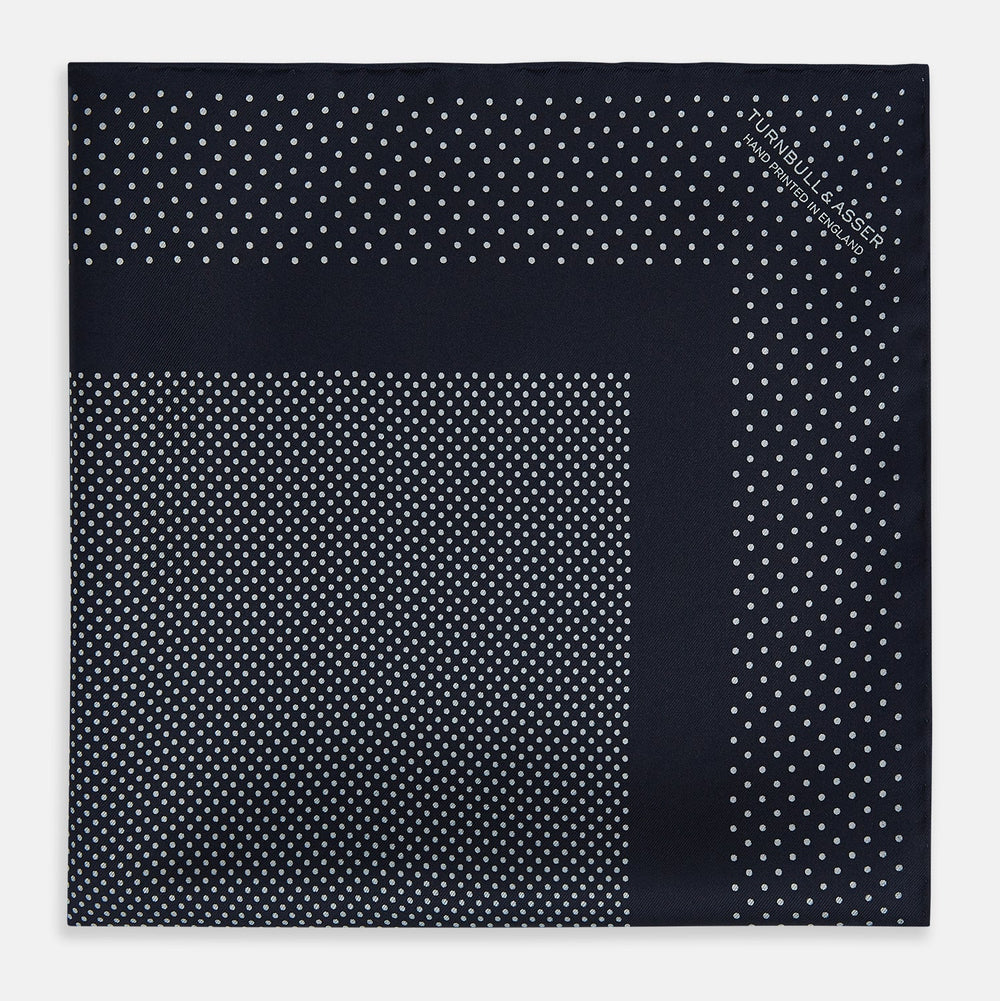 The Turnbull & Asser Navy and Grey Dot Silk Pocket Square features a neatly folded design with small grey dots on navy silk and a solid border, showcasing both sides of the luxurious fabric.