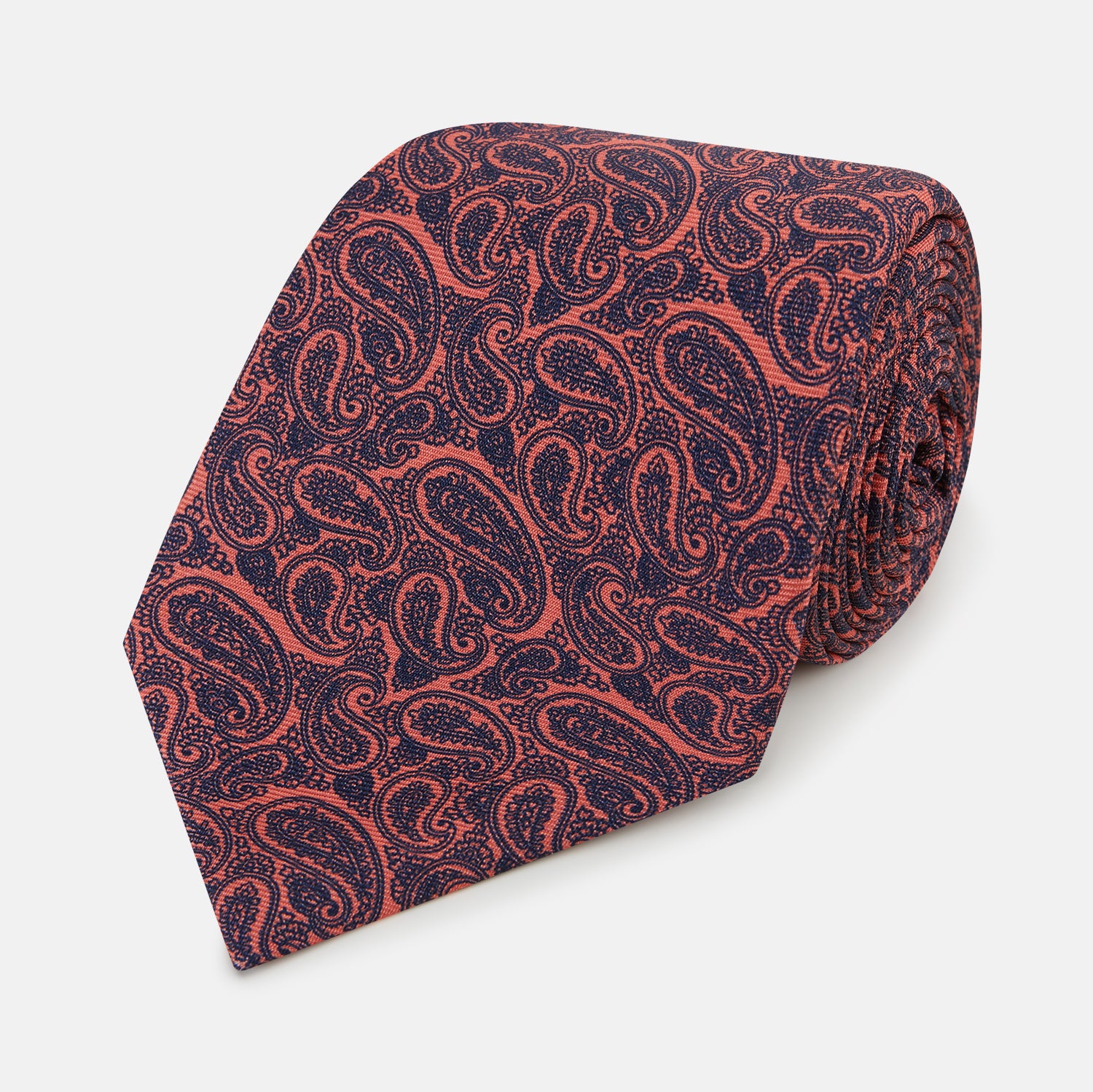 View 1 of product The Turnbull & Asser Orange Paisley Silk Tie, crafted from fine English silk, features an elegant paisley pattern and is stylishly rolled up on a plain white background.