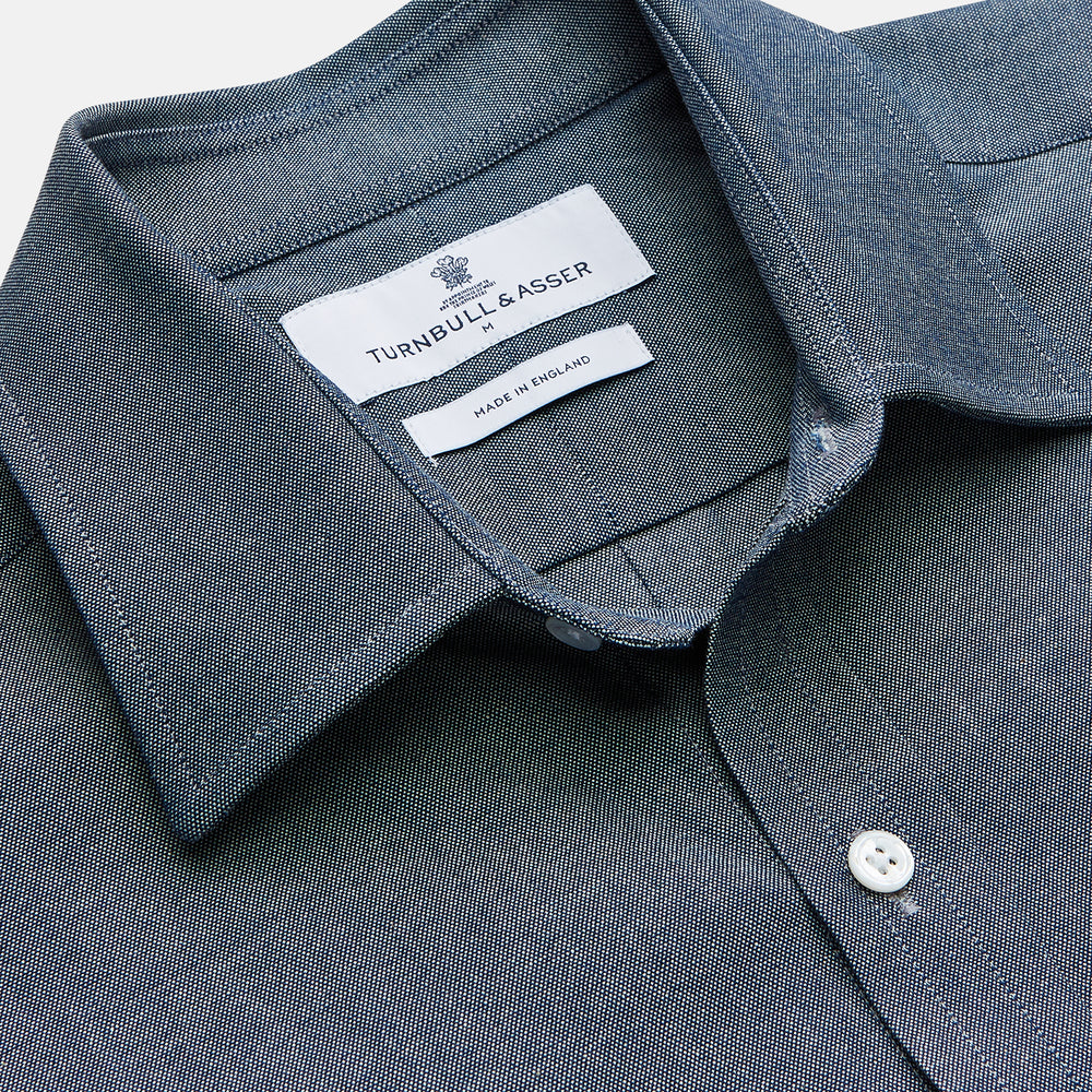 The Turnbull & Asser Blue Weekend Fit Oxford Finch Shirt features a Derby collar, chest pocket, white buttons, and classic fit—part of the Weekend Fit shirts collection—laid flat on a white background.