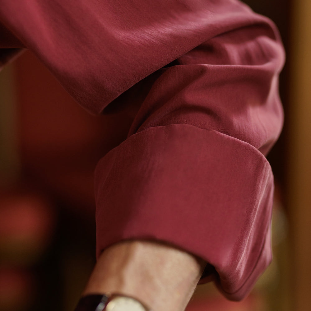 The Turnbull & Asser Burgundy Silk Shirt features a T&A collar and 3-button cuffs, offering a refined alternative to a black tie for modern style. Displayed folded on a white background.