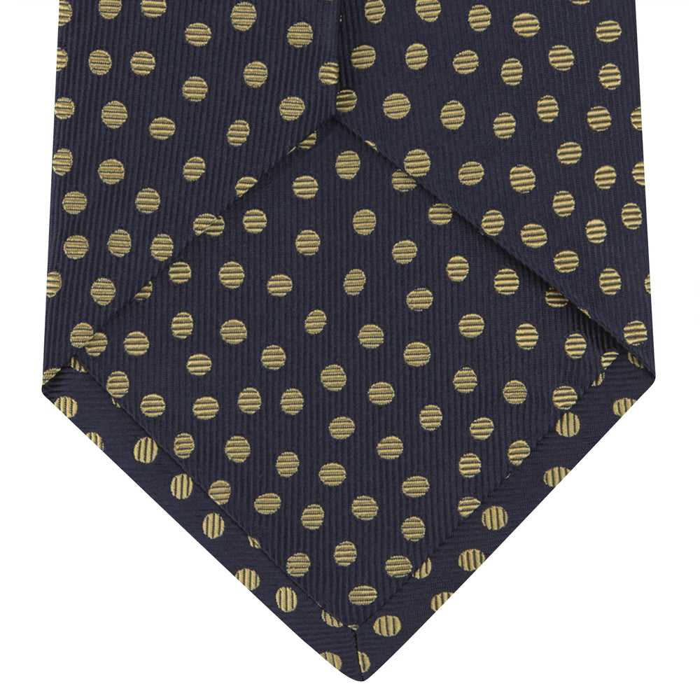 The Turnbull & Asser Navy and Gold Paint Spot Silk Tie features evenly spaced gold spots on classic navy silk, rolled and displayed on a plain white background—ideal for complementing your favorite office shirt.