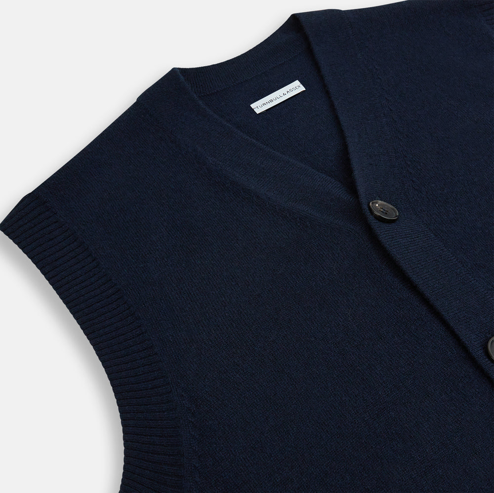 The Turnbull & Asser Navy Cashmere V-neck Sleeveless Cardigan features a button-up closure and two front pockets, ideal for elegant, gentleman-inspired looks, shown on a plain white background.