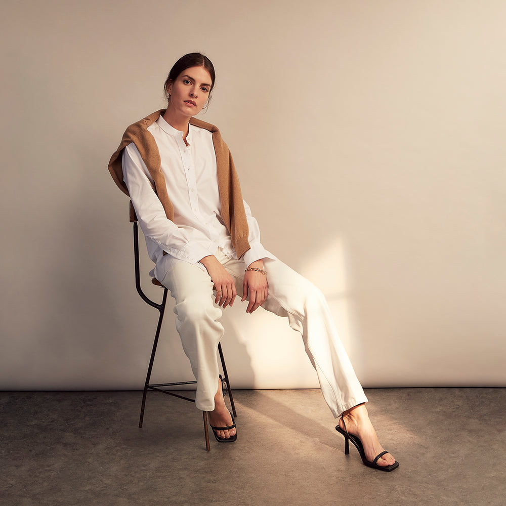 The White Cotton Lauren Shirt by Turnbull & Asser, featuring a stand collar, button-down front, and elongated body, is laid flat on a plain white background.