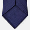 View 3 of product The PLAIN HERRINGBONE NAVY TIE by Turnbull & Asser, crafted from silk with a subtle pattern, is elegantly rolled and displayed against a plain white background.