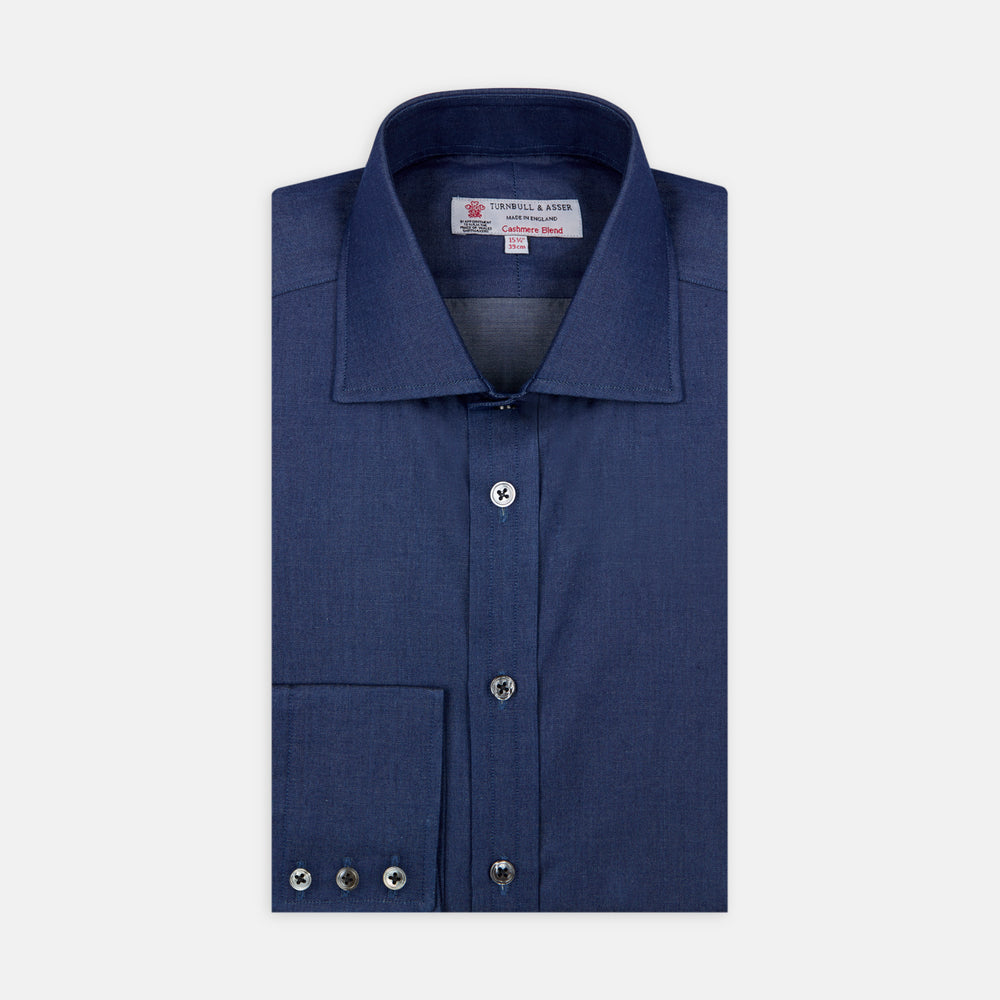 The Turnbull & Asser Dark Blue Denim-Cashmere Shirt features a Regent collar, long sleeves, and 3-button cuffs, neatly folded and displayed on a plain light background.