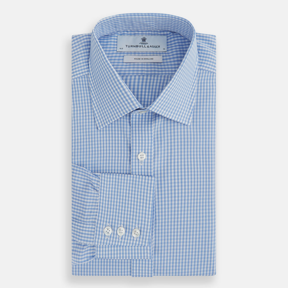 The Turnbull & Asser Light Blue Gingham Check Shirt features a T&A collar, 3-button cuffs, classic gingham pattern, and white buttons down the front, shown laid flat on a white background.
