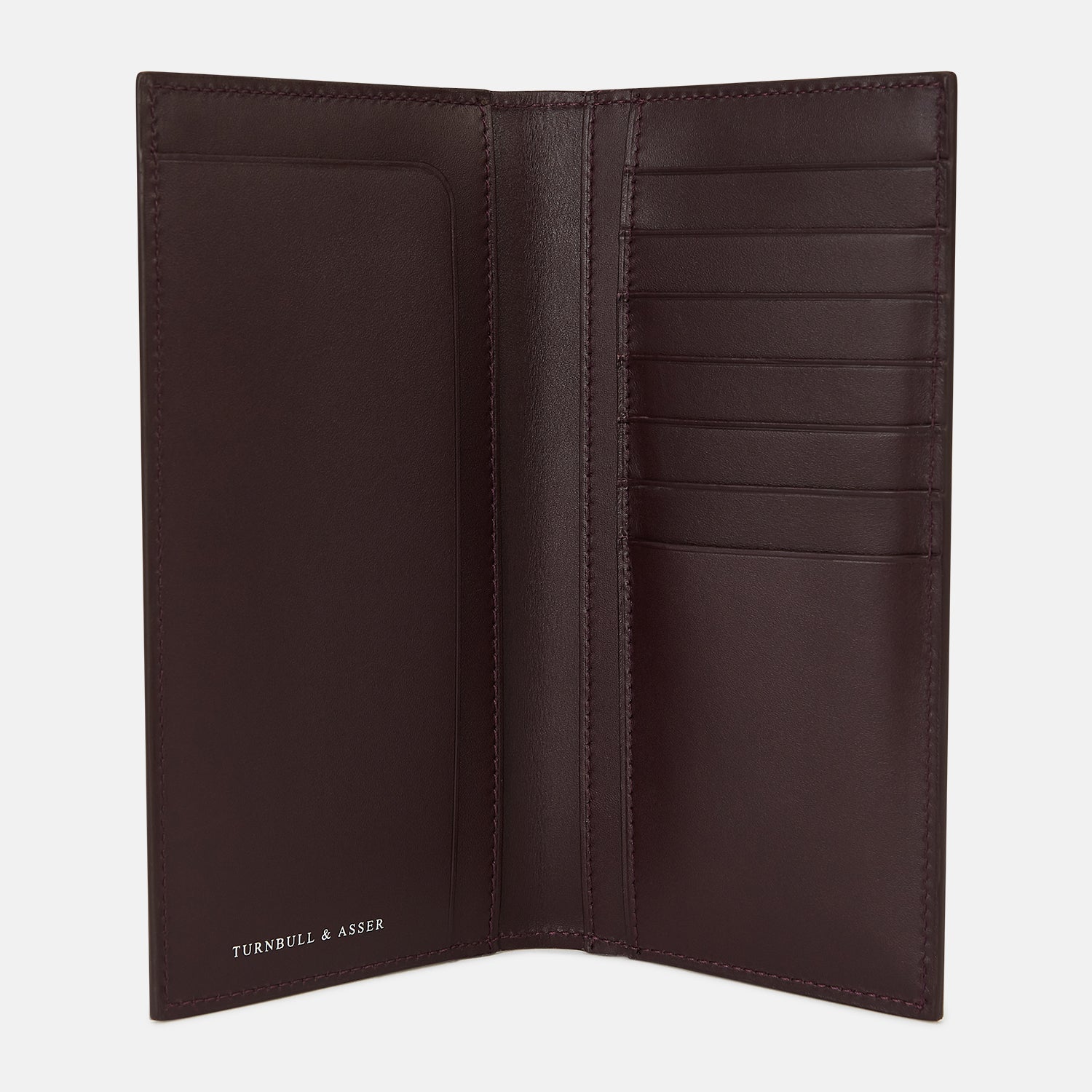 View 2 of product The Turnbull & Asser Burgundy B Cut Continental Wallet, with smooth, unadorned surfaces and visible edge stitching, is pictured closed in rich burgundy Italian leather against a white background.
