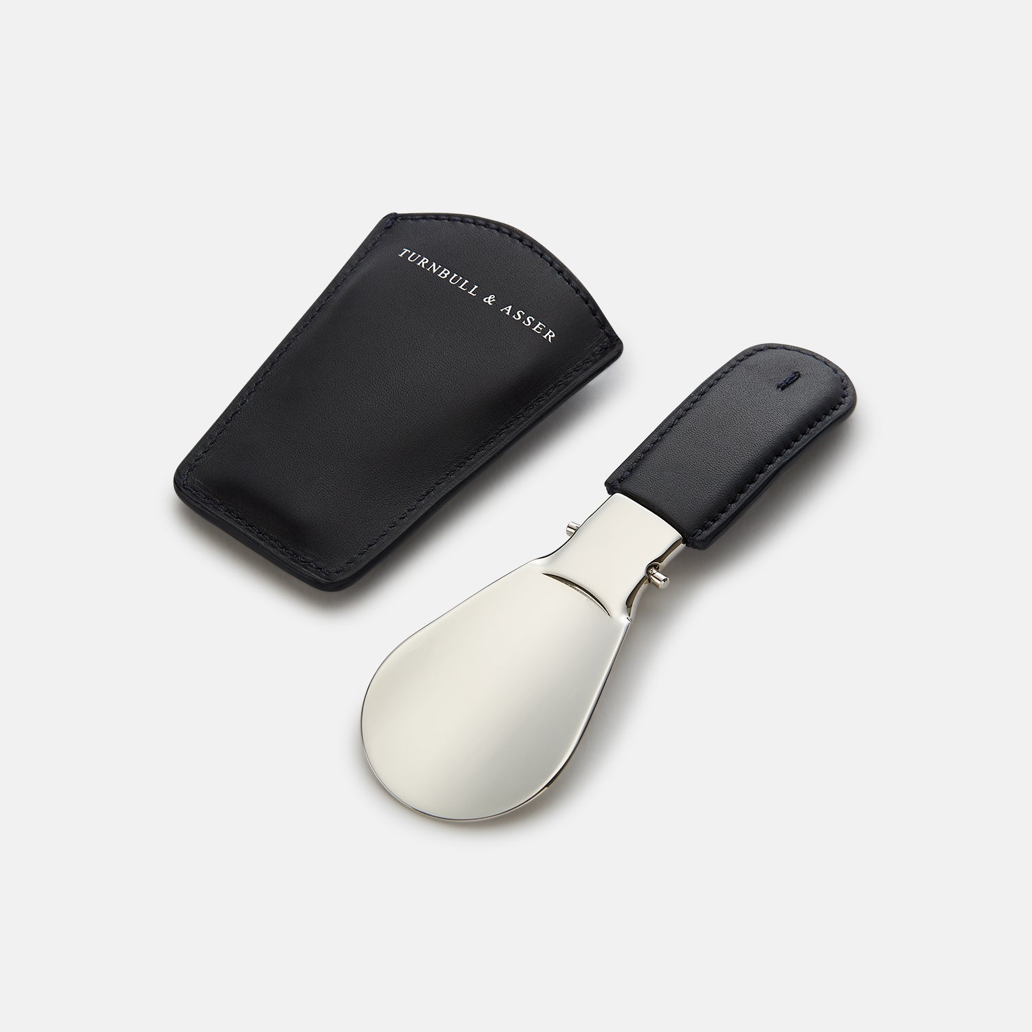 View 3 of product The Turnbull & Asser Forest Green Travel Shoe Horn features a wide, smooth metal blade and a forest green leather handle, shown against a plain white background.