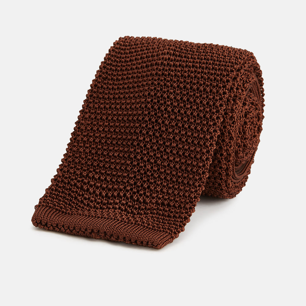 The Turnbull & Asser KNITTED BROWN SILK PLAIN TIE—a stylish, textured accessory—appears rolled up on a white background, perfect for elevating smart outfits.