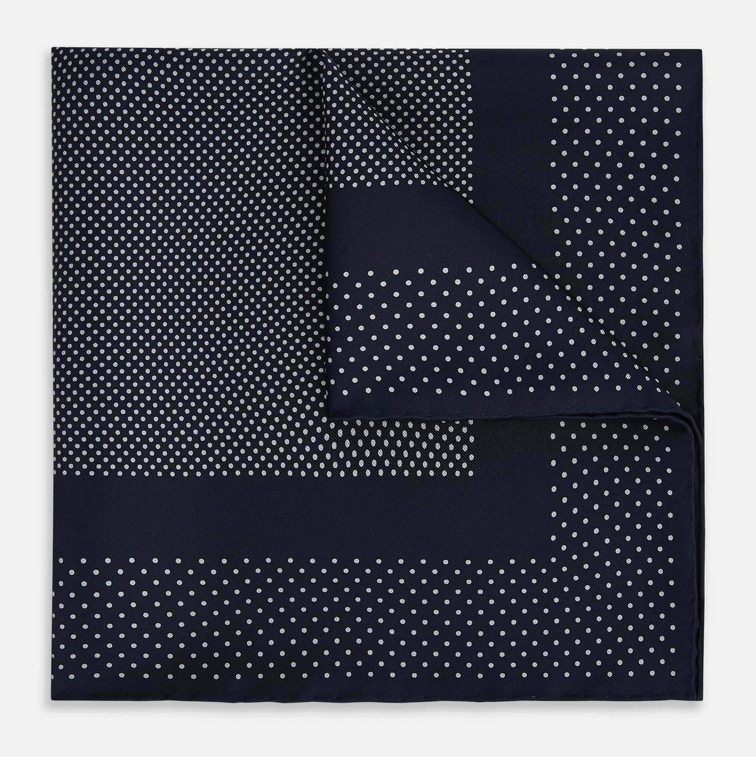 View 1 of product The Turnbull & Asser Navy and Grey Dot Silk Pocket Square features a neatly folded design with small grey dots on navy silk and a solid border, showcasing both sides of the luxurious fabric.