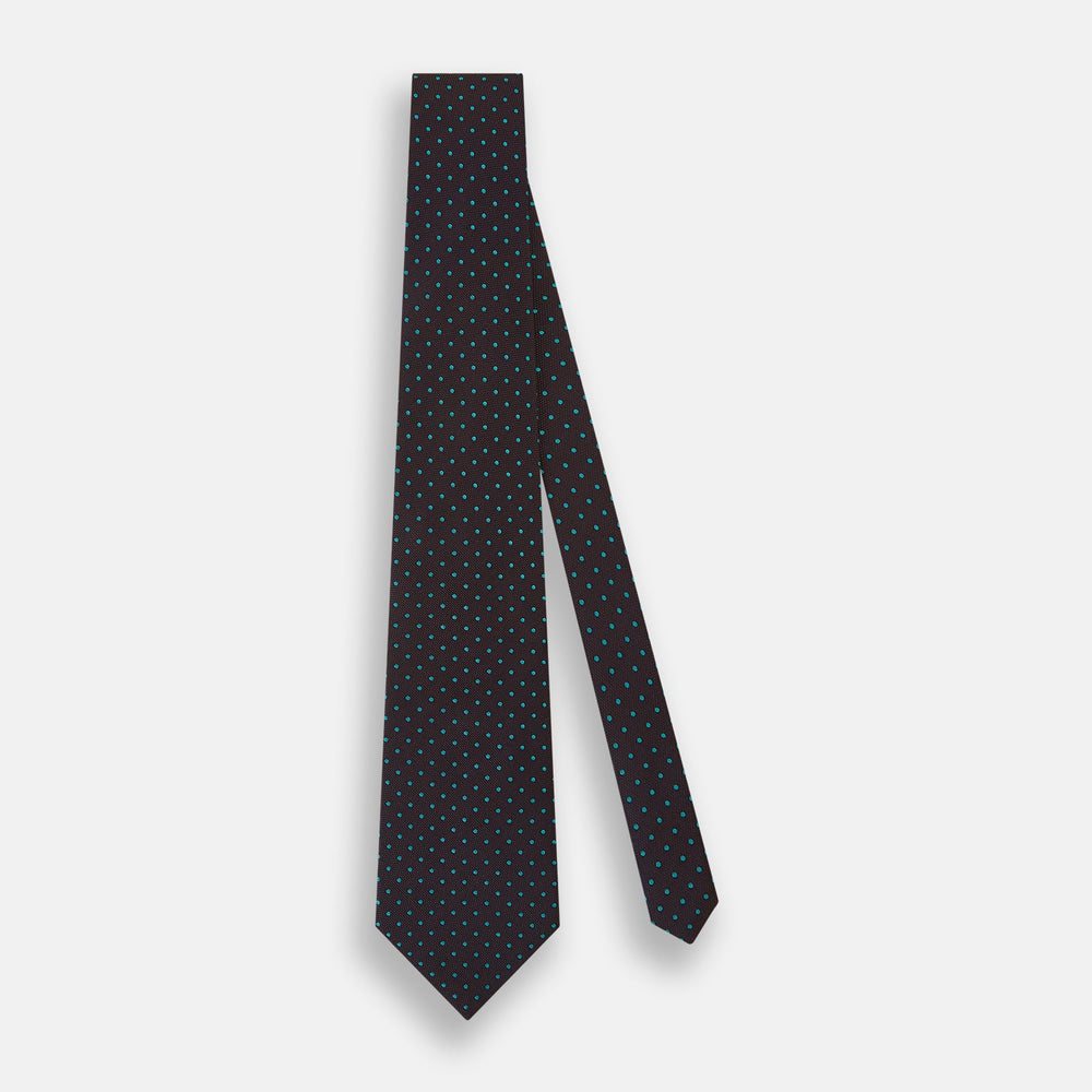 The Turnbull & Asser Turquoise and Forest Green Micro Dot Silk Tie is rolled up, showcasing evenly spaced micro dots on silk, displayed against a plain white background.