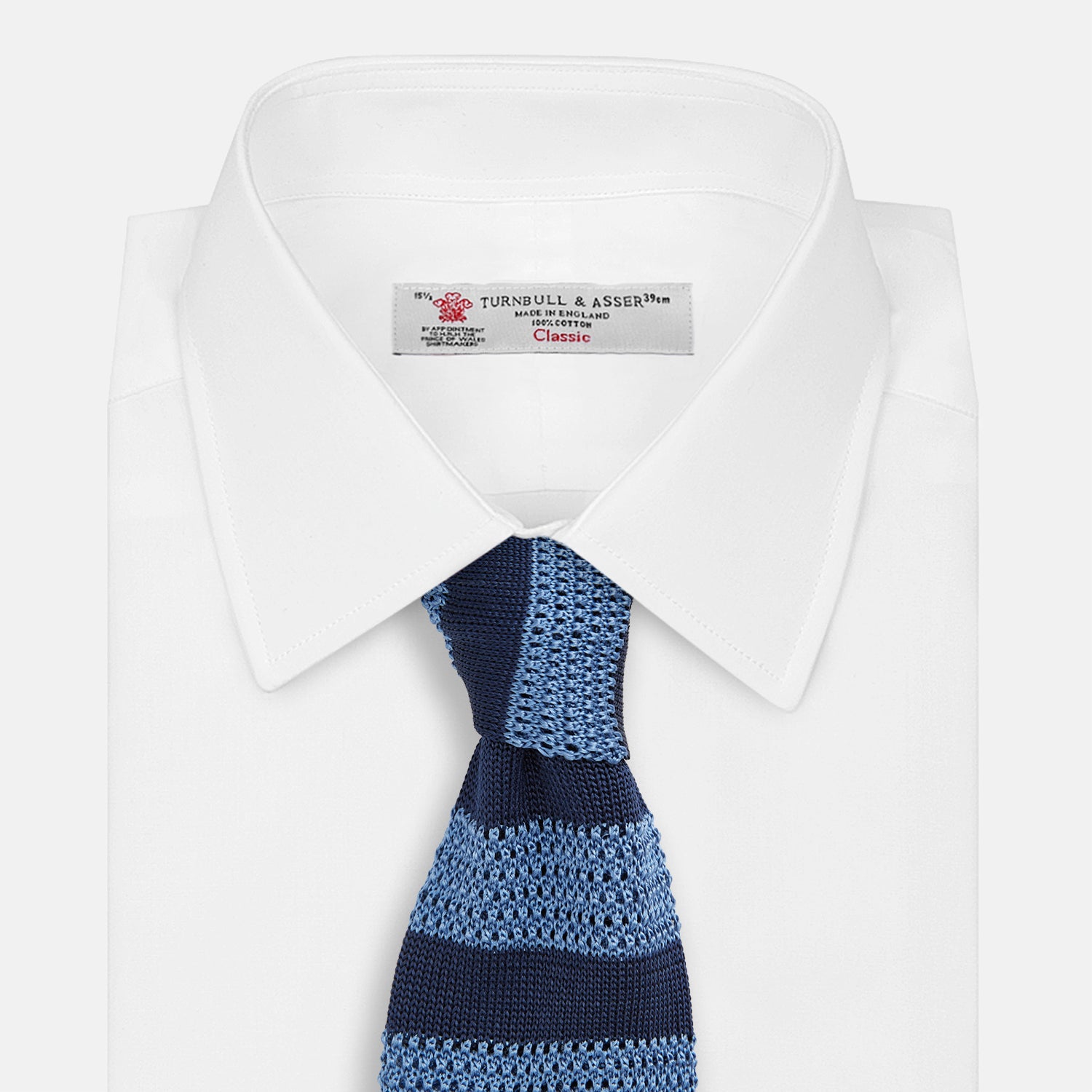 View 2 of product The Turnbull & Asser Navy and Blue Square tipped knitted tie features horizontal stripes and a rolled-up silk design, elegantly displayed on a plain white background.