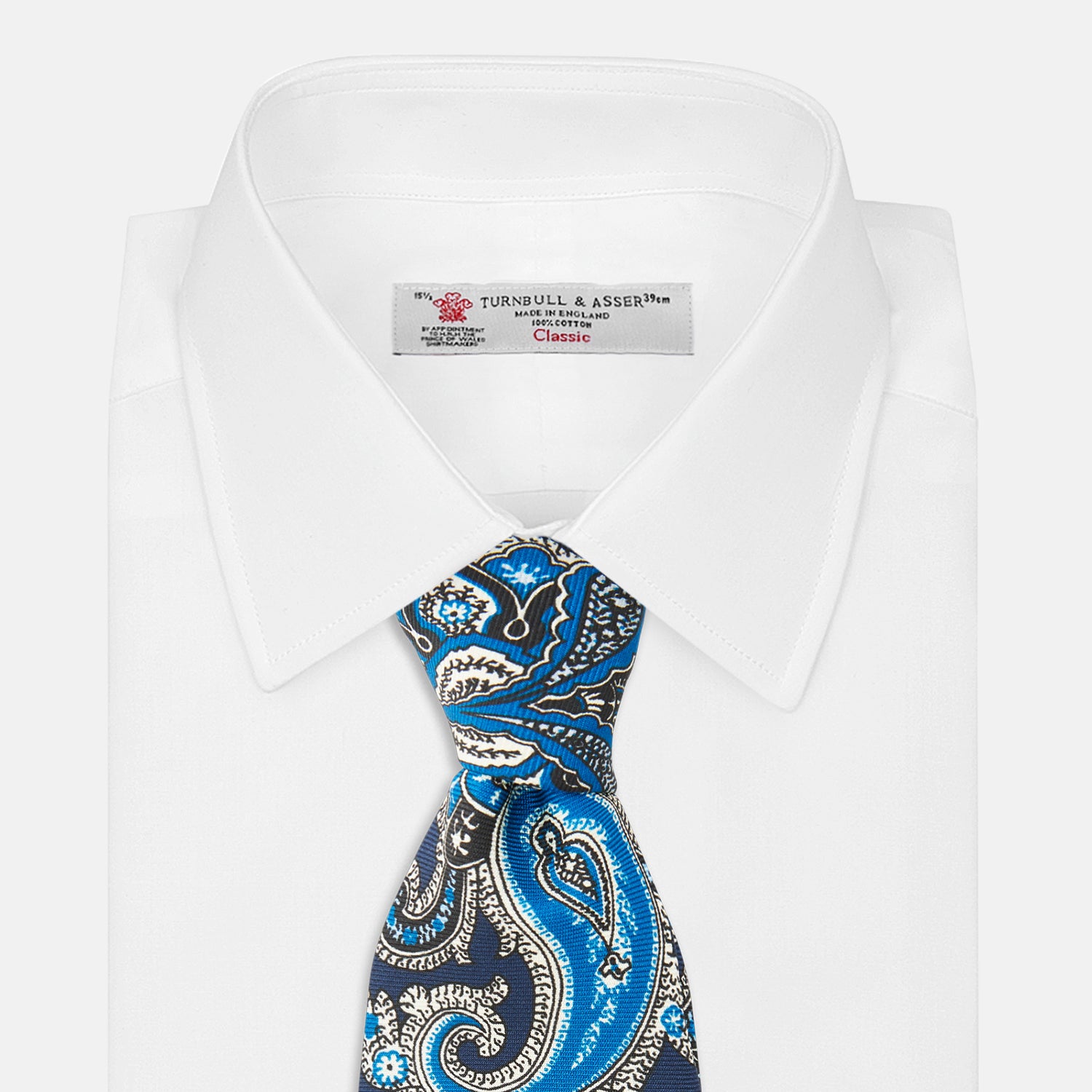 View 2 of product The Turnbull & Asser Blue and Navy Twisted Paisley Silk Tie displays intricate blue, white, and black details, rolled up against a plain white background.