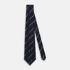 View 2 of product The Turnbull & Asser Navy Zigzag Jacquard Silk Tie is crafted from fine English silk, featuring a navy base with thin white zigzag stripes and shown rolled up on a plain white background.
