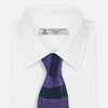 View 2 of product The KNITTED STRIPE PURPLE TIE by Turnbull & Asser features bold dark blue and purple stripes, making it an essential smart accessory. Shown rolled up on a white background.