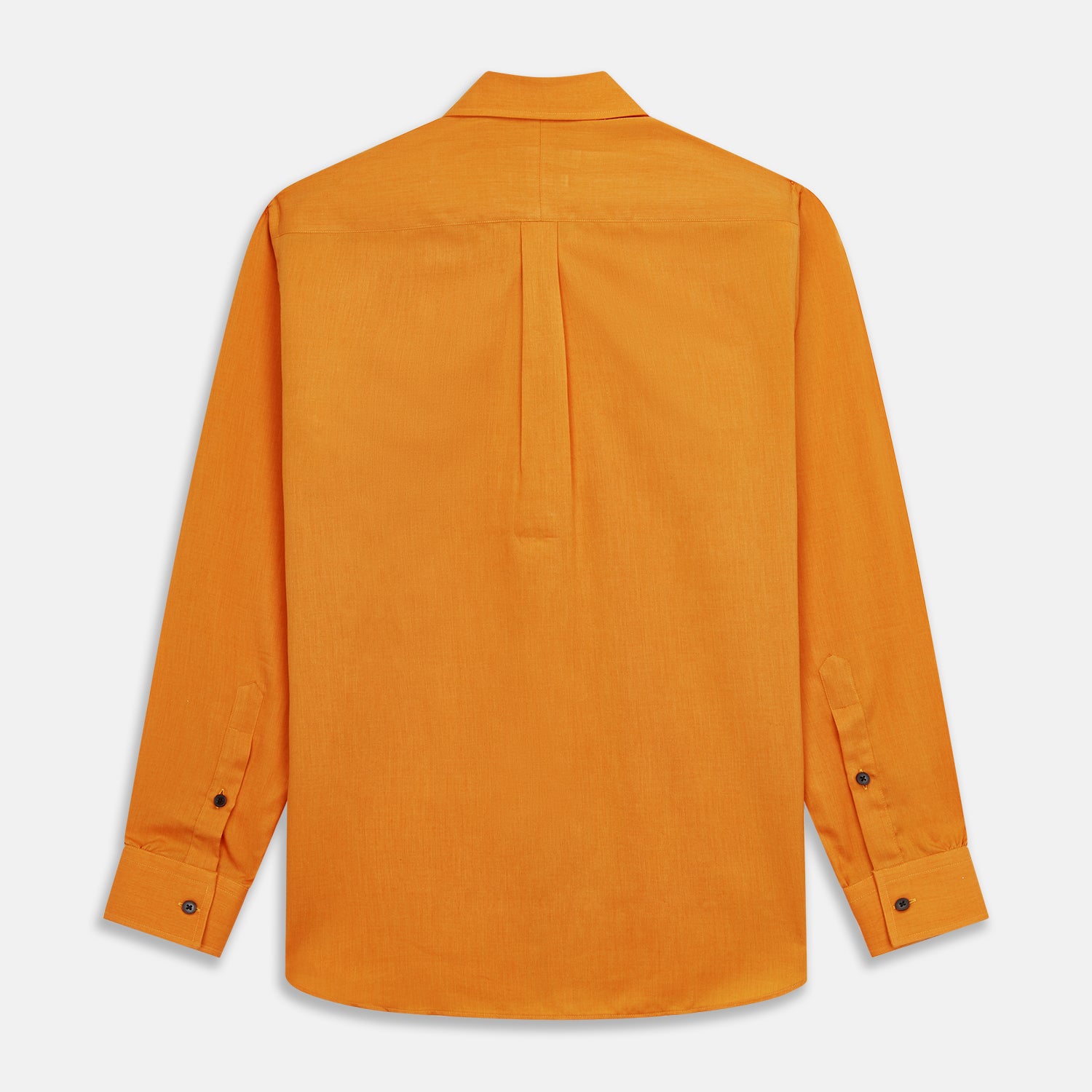 View 8 of product A man stands against a tan background, wearing a Turnbull & Asser Orange Weekend Fit Cotton & Wool Shirt with Derby Collar and 1 Button Cuffs, tucked into dark blue dress pants with a black belt and shoes. He has one hand in his pocket.