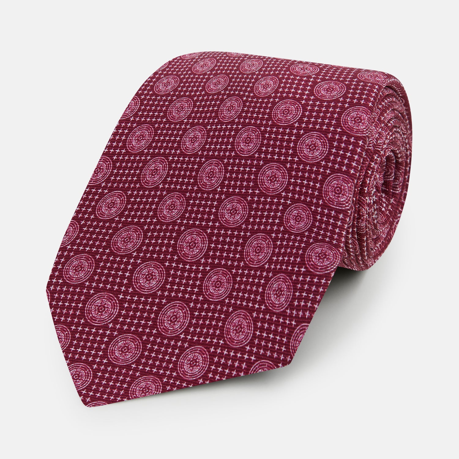 View 1 of product The Turnbull & Asser Burgundy Medallion Printed Silk Tie features small circular medallions and subtle light pink diagonal lines, crafted from fine English silk and displayed on a plain white background.