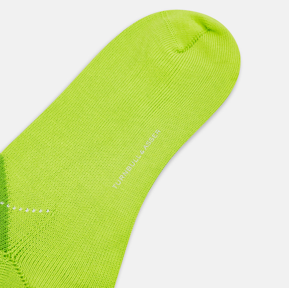The Lime Check Mid-Length Sock by Turnbull & Asser features a green and yellow argyle pattern with a ribbed cuff, crafted from comfortable cotton material, and is shown on a plain light background.