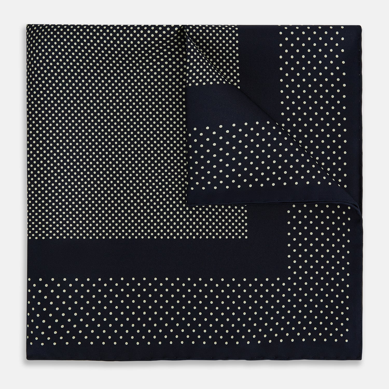 View 1 of product The Turnbull & Asser Navy and Cream Dot Silk Pocket Square features small cream dots, a border design, and displays handmade craftsmanship with one corner folded to show the reverse side.