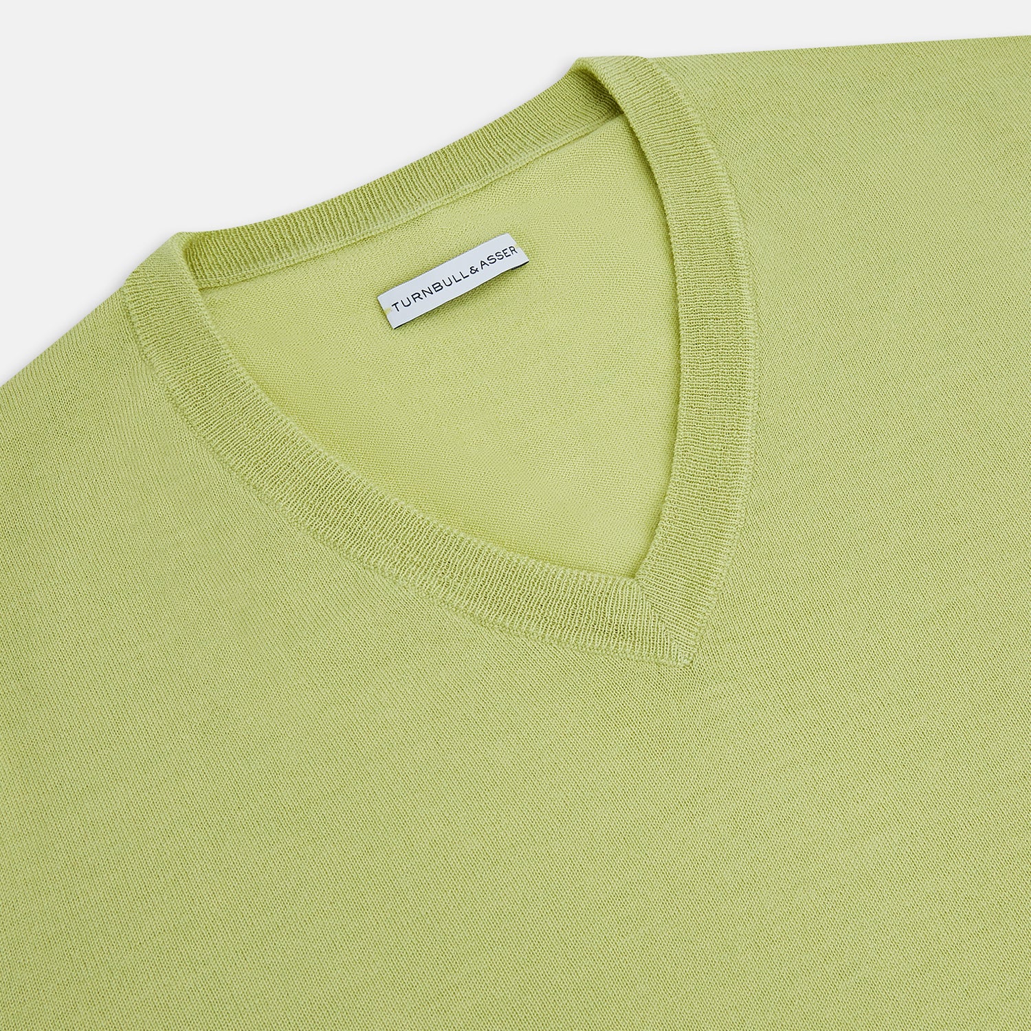 View 2 of product The Turnbull & Asser Melon Green Merino V-Neck Jumper is shown on a white background, featuring long sleeves, ribbed cuffs, and a ribbed hem.