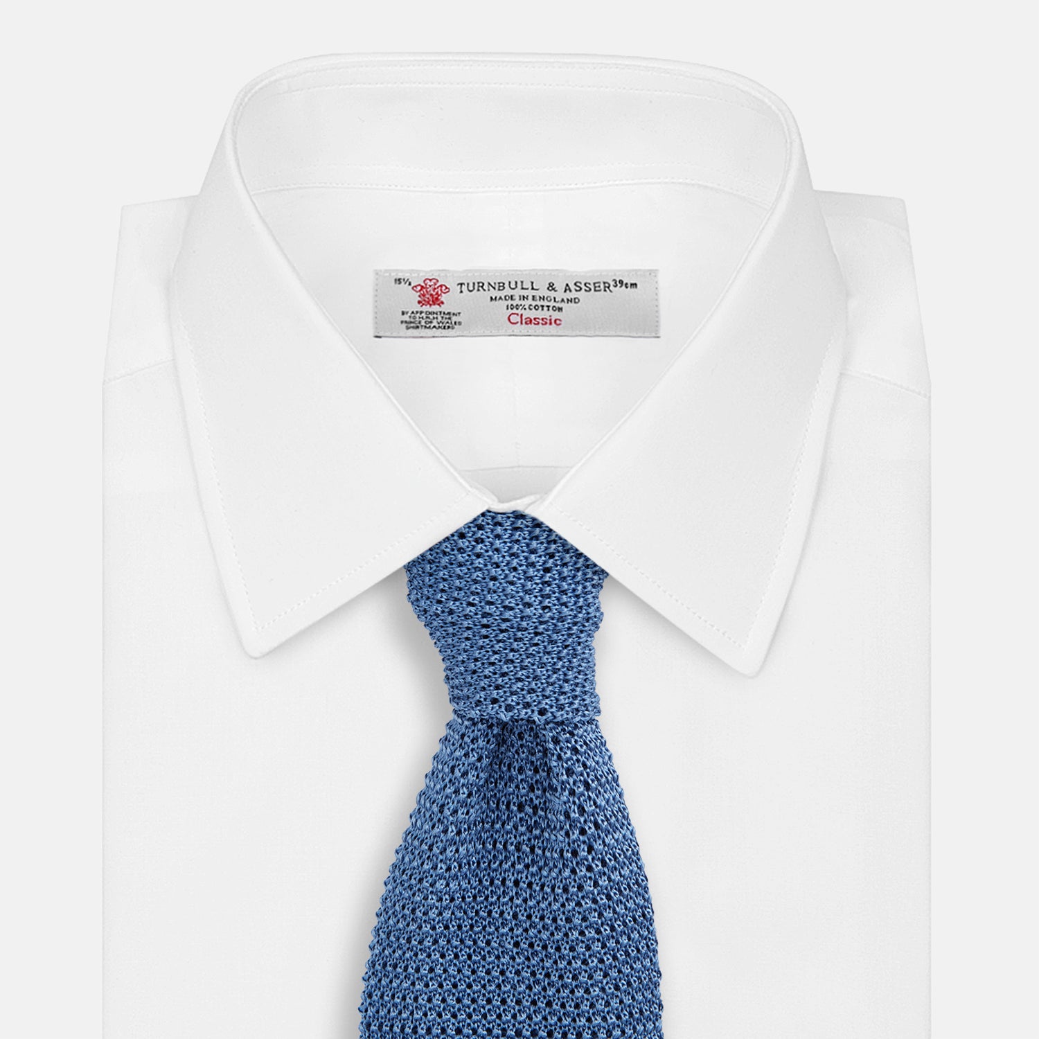 View 2 of product The Turnbull & Asser Knitted Mid Blue Silk Plain Tie features a textured knit and is shown rolled up on a plain white background—a refined accessory that pairs perfectly with formal shirts.
