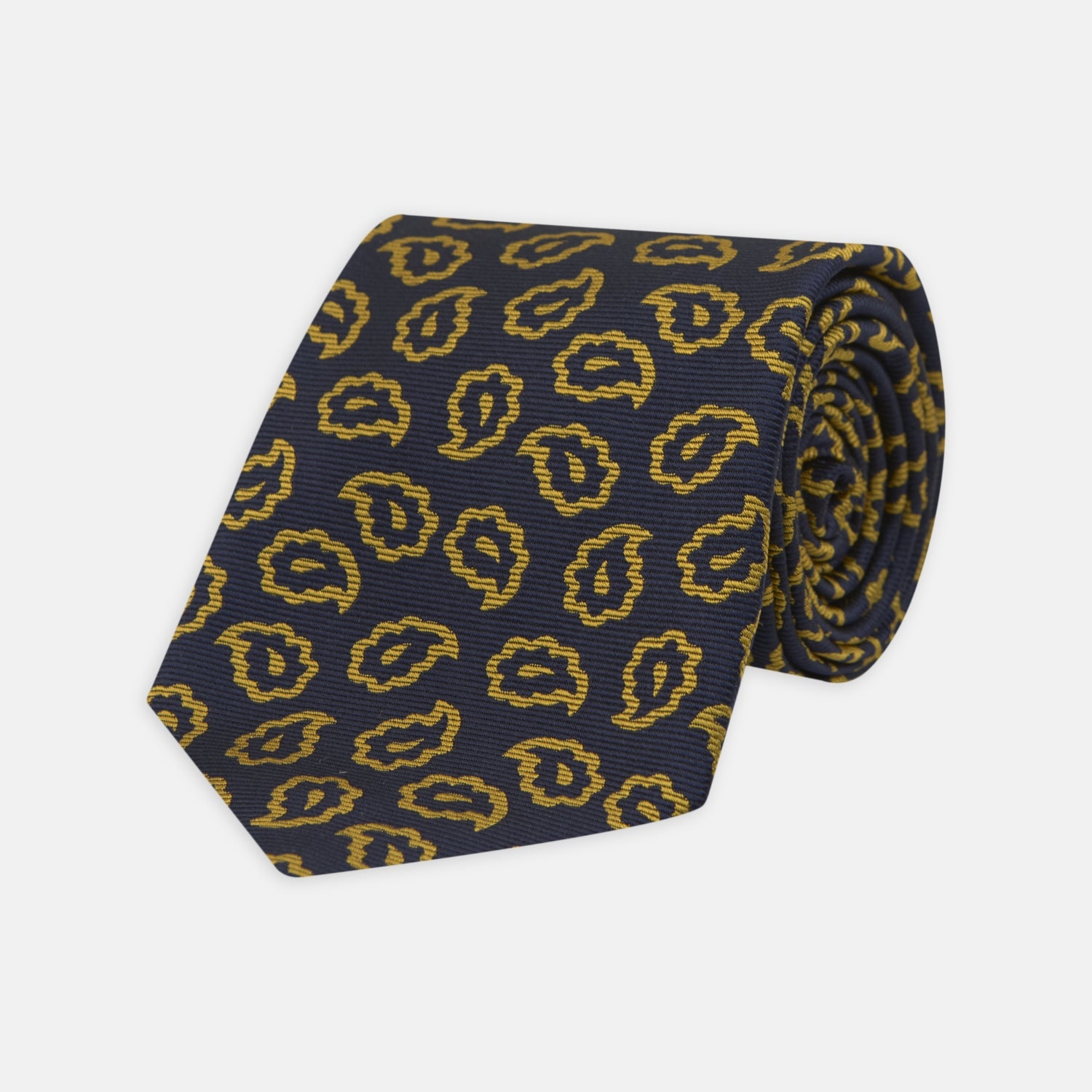 View 1 of product The Navy and Gold Petal Paisley Silk Tie by Turnbull & Asser features a repeating yellow abstract pattern, neatly rolled on a white background.