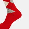 View 4 of product Mid-length orange wool socks by Turnbull & Asser, featuring a classic check pattern in orange, beige, and gray, reminiscent of timeless wool socks, displayed on a plain light background.