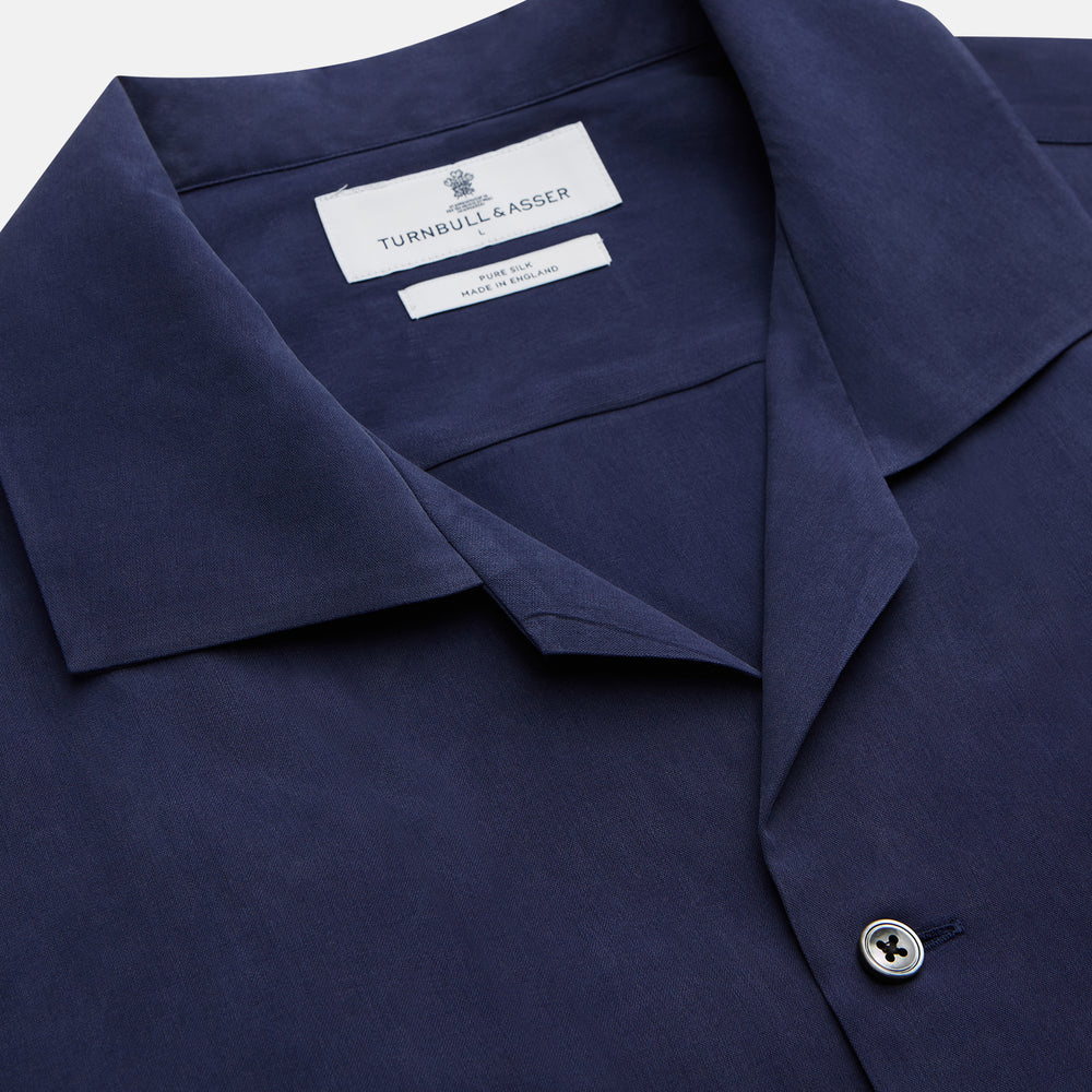 The Navy Silk Holiday Fit Phillips Shirt by Turnbull & Asser features short sleeves, a revere collar, and three front patch pockets, shown laid flat on a white background.