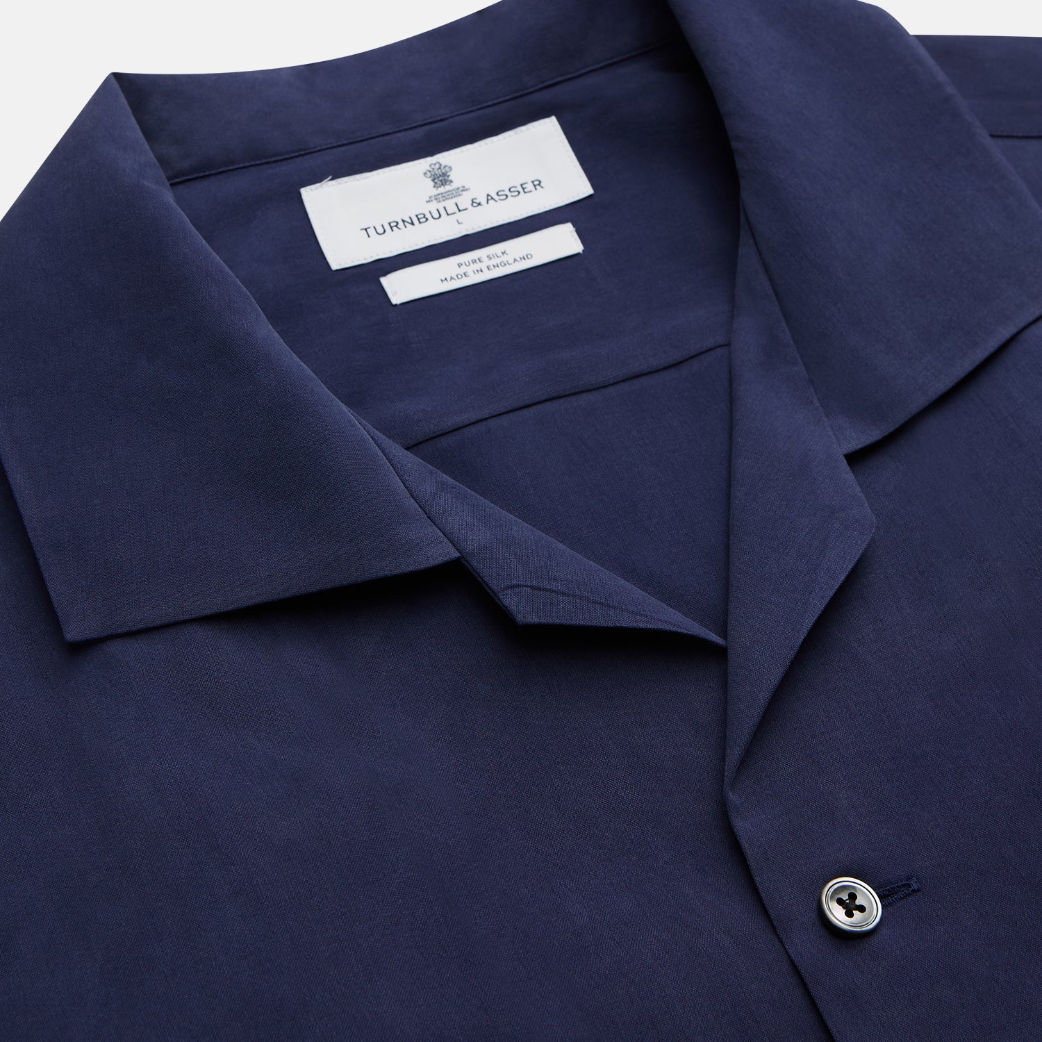View 4 of product The Navy Silk Holiday Fit Phillips Shirt by Turnbull & Asser features short sleeves, a revere collar, and three front patch pockets, shown laid flat on a white background.