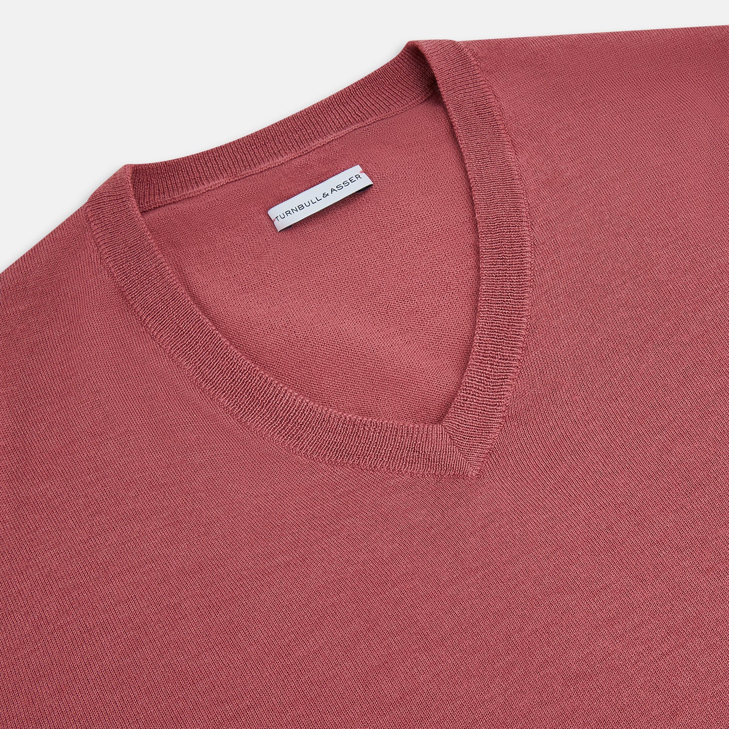 View 2 of product The Turnbull & Asser Antique Pink Merino V-Neck Jumper features ribbed cuffs, hem, and neckline in a soft antique pink, shown on a plain white background. Part of our knitwear collection.