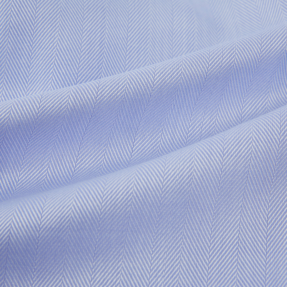 The Turnbull & Asser Blue Herringbone Tailored Fit Shirt with Kent Collar features a formal light blue design, long sleeves, white buttons, and a 3-button cuff. Shown flat on a white background.