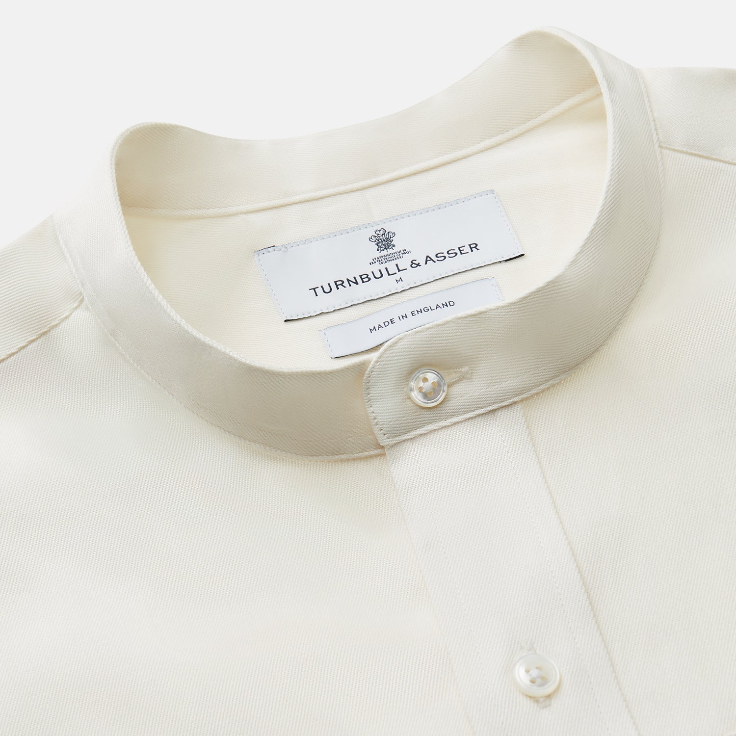 View 2 of product The Turnbull & Asser Cream Cotton Weekend Fit Unwin Shirt features long sleeves, a stand collar, and two chest pockets, shown laid flat on a white background.