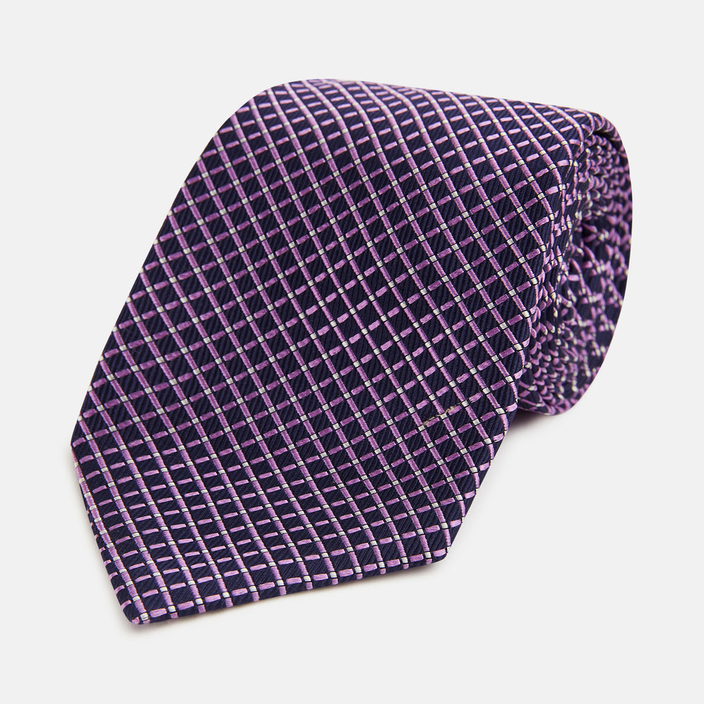 A rolled-up Turnbull & Asser Purple and Navy Diamond Silk Tie displays its elegant grid pattern of light pink and white lines on a white background.