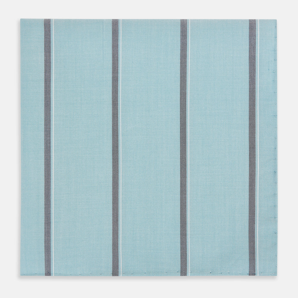 The Turnbull & Asser Light Sage Track Stripe Hand-Rolled Handkerchief features vertical thin white and thicker dark gray stripes, neatly folded with a simple modern design, made in England.