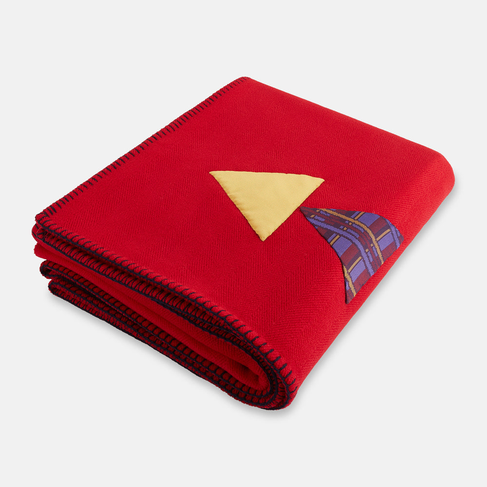 The Turnbull & Asser Red Applique Hand Stitched Lambswool Blanket features black-stitched edges and handsewn tie silk patches, including a yellow triangle and plaid triangle arranged to form a stylized fish.