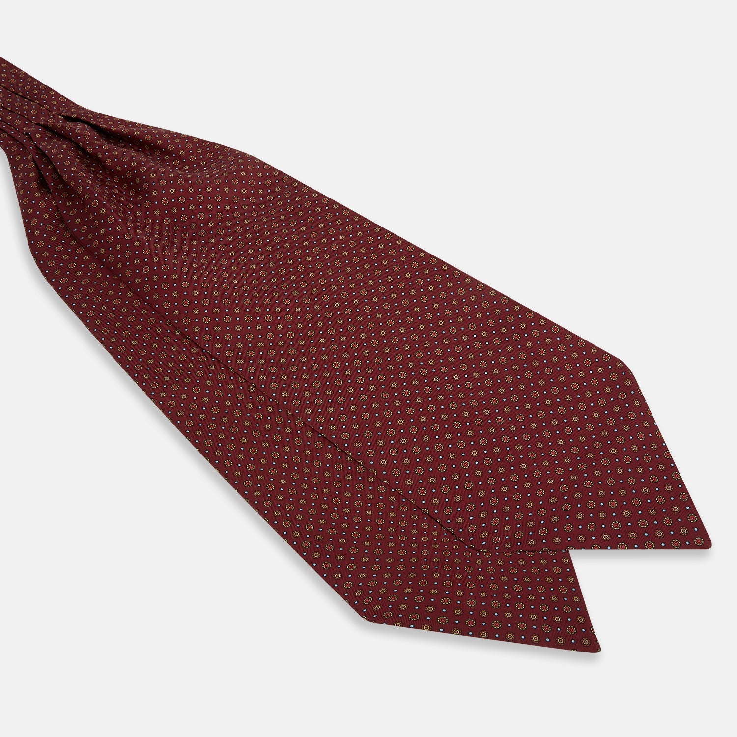 View 3 of product The Great Gatsby Burgundy Printed Silk Cravat by Turnbull & Asser features a maroon silk fabric with a small yellow and blue geometric pattern, subtle sheen, and neatly finished edges for an elegant, Gatsby-inspired formal accessory.