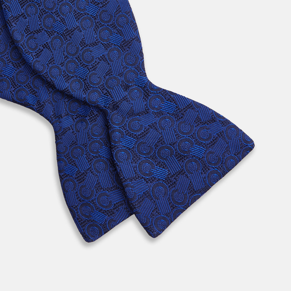 The Turnbull & Asser Electric Blue Motif Silk Bow Tie features subtle circular and swirl designs, shown on a plain white background—perfect for elevating formal attire.