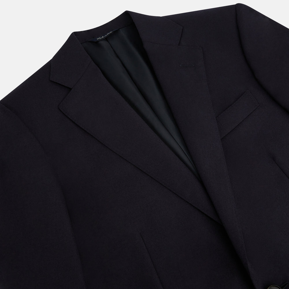 The Turnbull & Asser Short Navy Single Breasted Suit is shown flat on a white background, with a notch lapel jacket featuring two front pockets and matching trousers neatly folded underneath.