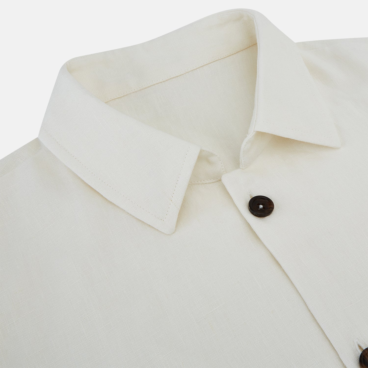 View 2 of product The Vanilla Linen Holland Shacket by Turnbull & Asser, a white Irish linen button-up with a collar, brown buttons, and four pockets, is laid flat on a white background—perfect as lightweight outerwear.