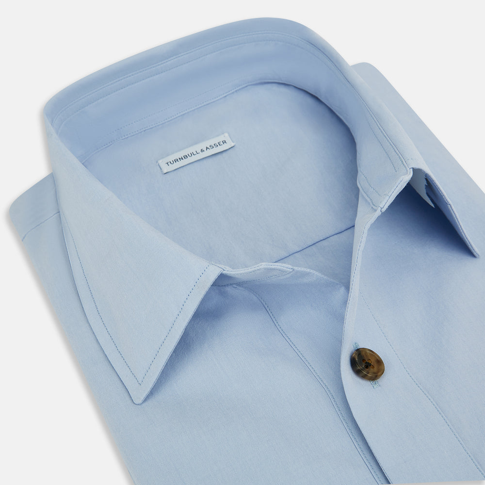 The Turnbull & Asser Pale Blue Hyde Overshirt is a long-sleeve, sanforised cotton button-up with a single chest pocket and dark buttons, shown on a plain white background.