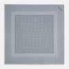 View 4 of product The Turnbull & Asser Grey Dot Silk Pocket Square features a light gray silk design with navy polka dots and a solid border. Elegantly handmade, it is shown with one corner folded to display both sides.
